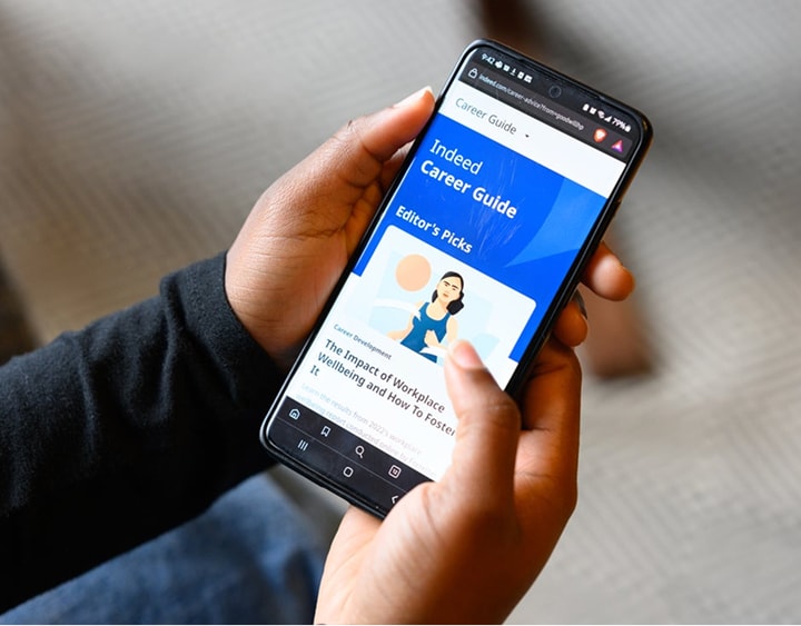 Hands holding a smartphone displaying the Indeed Career Guide app with a blue header.