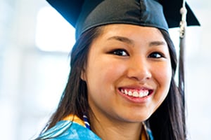 Graduate smiling in cap and gown during graduation ceremony.