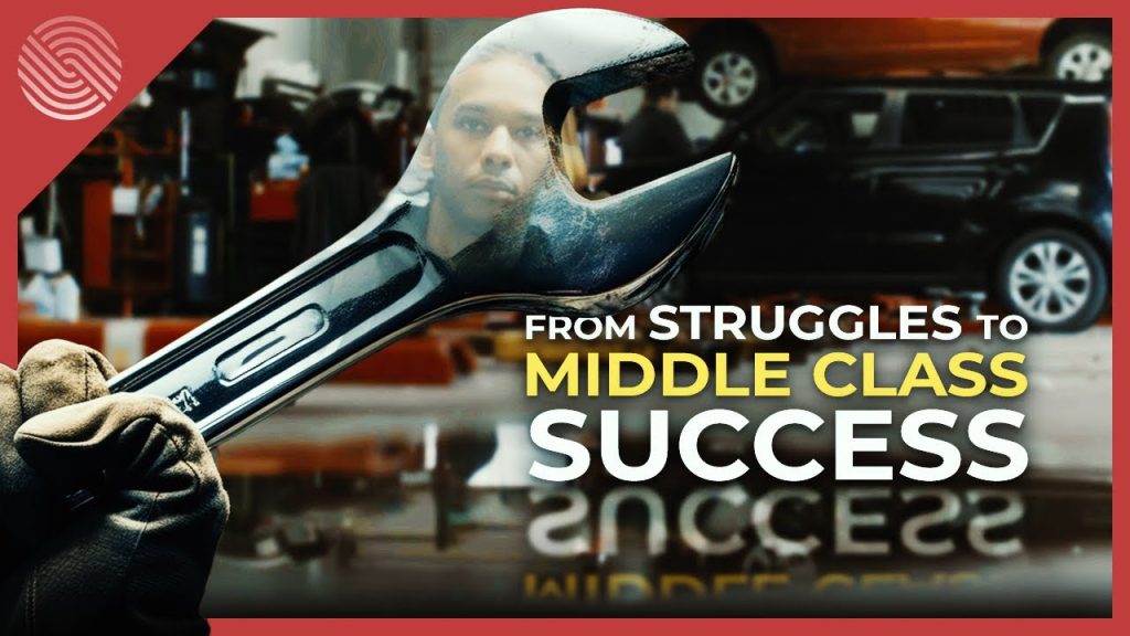 Man's reflection in a chrome wrench held by a gloved hand inside an auto repair shop