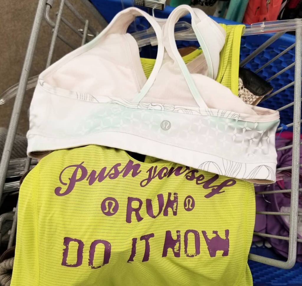 White sports bra draped over a neon yellow running shirt with purple text.