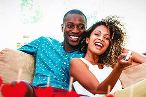 Smiling couple lounging on a sofa at home, woman holding a remote.