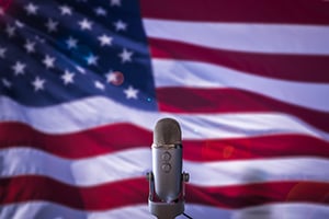 Vintage microphone in front of a waving American flag