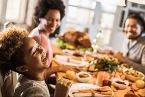 Friends laughing and sharing a colorful feast around a long dining table.