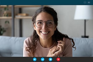 Smiling woman wearing glasses on a video call in a cozy living room.