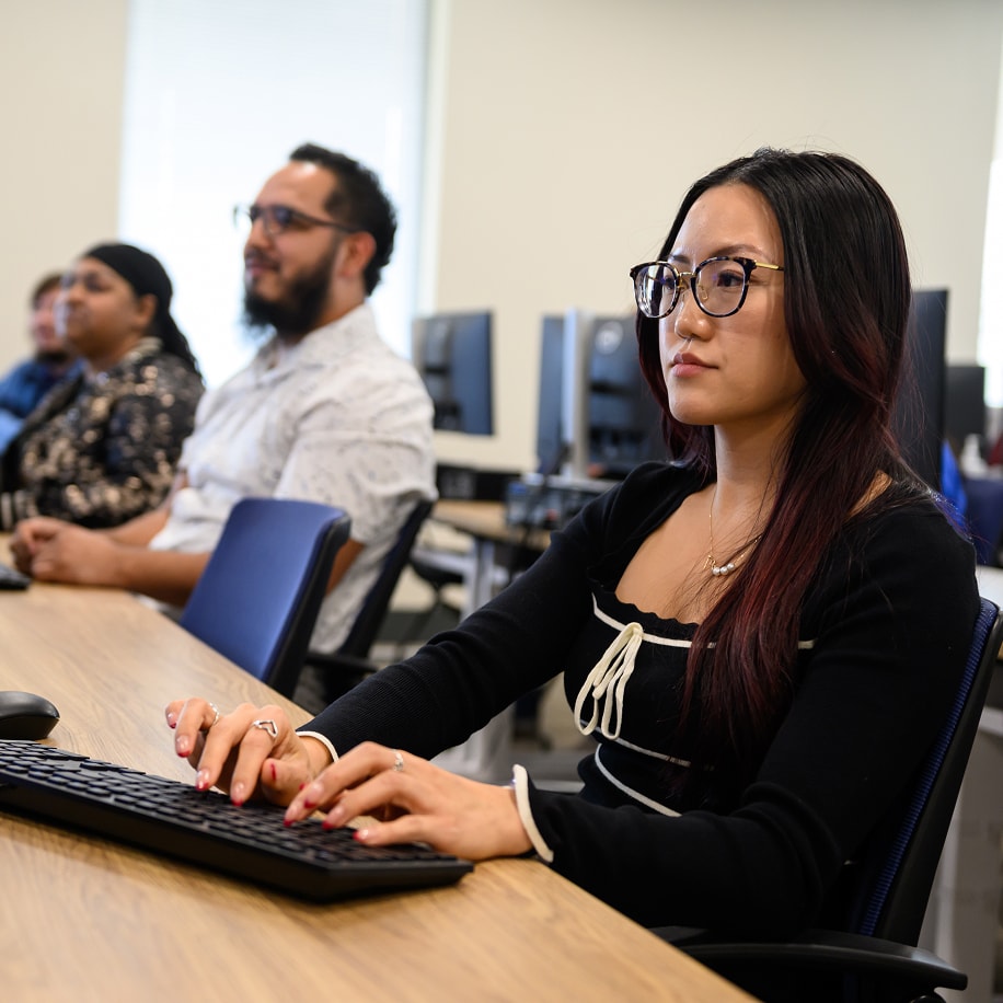 Young woman typing on a keyboard in a computer lab