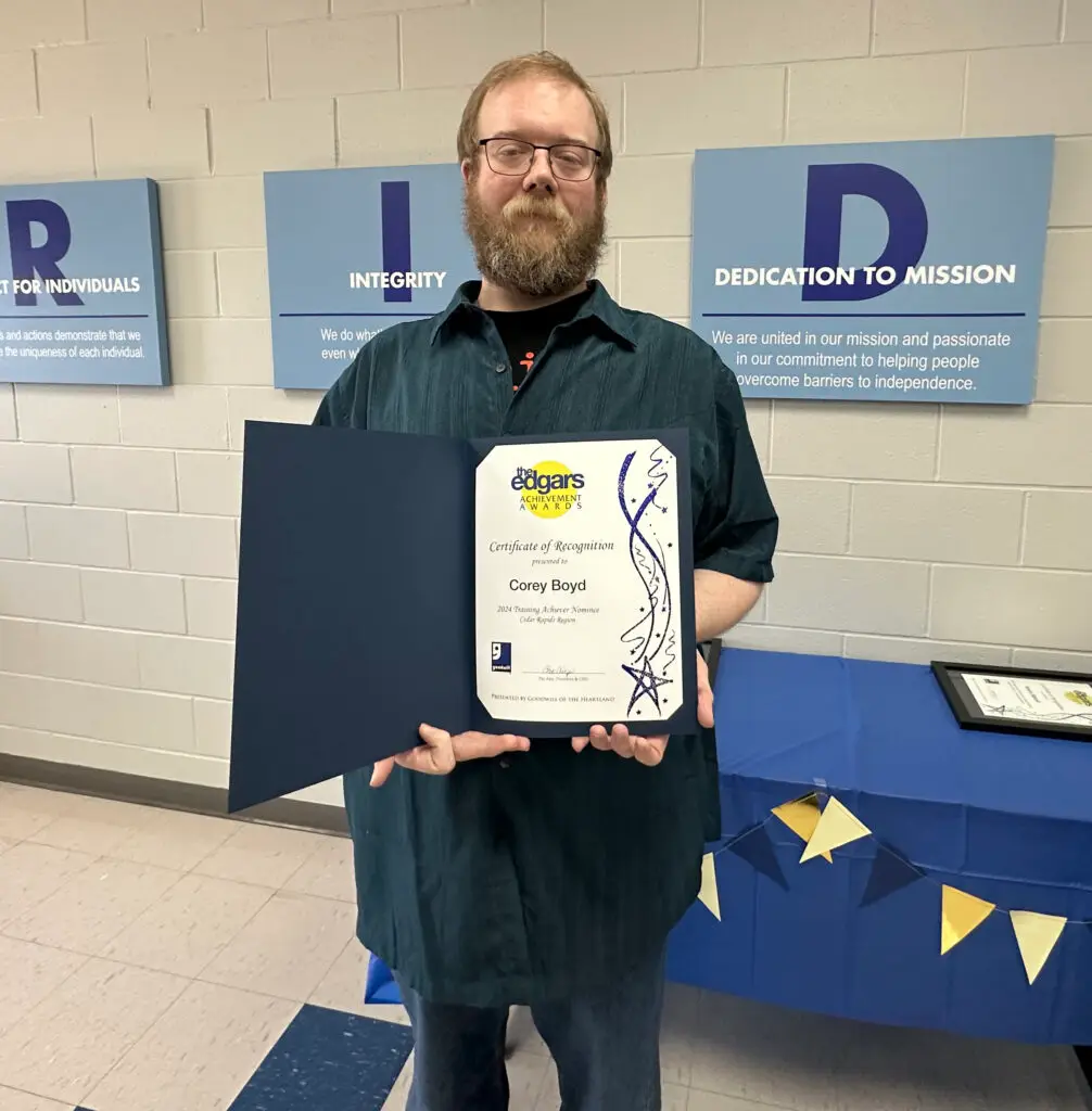 A picture of a man wearing black pants and a black button down holding a certificate