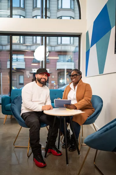 A men and a women sitting on blue chairs reviewing applications